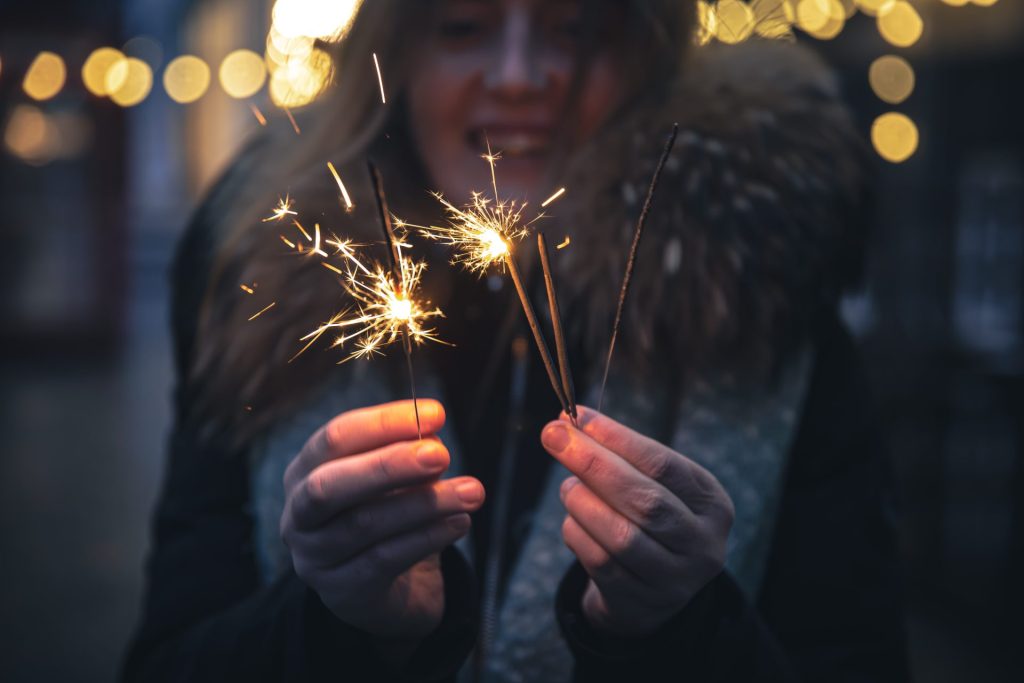Woman that is slightly blurred for effect is holding lit sparklers.
